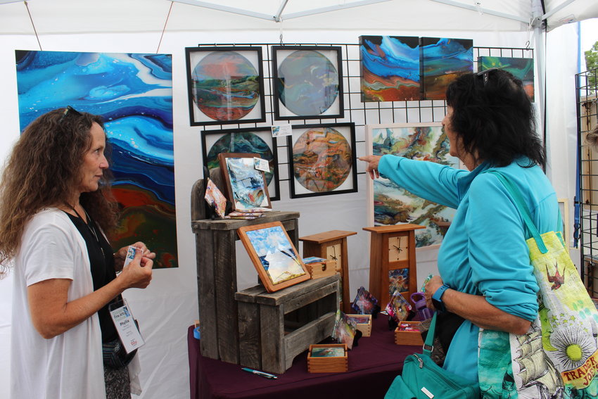 Buena Vista-based painter Phyllis Manning, left, talks about her work with attendees during the Golden Fine Arts Festival Aug. 20 in downtown Golden.